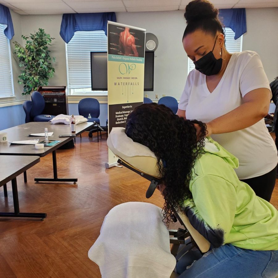 A student receives a massage in Foster Hall by a massage therapist during Wellness Day activities.
