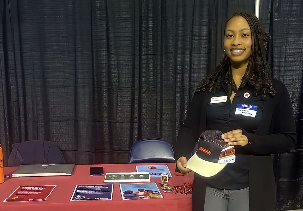 Senior Simone Henderson promotes the Omega Red hat, given to those who donate Power Red or twice as much. Henderson interacted with students attending the Career Fair in an attempt to promote the upcoming blood drive. “Sign up to save a life,” Henderson said.